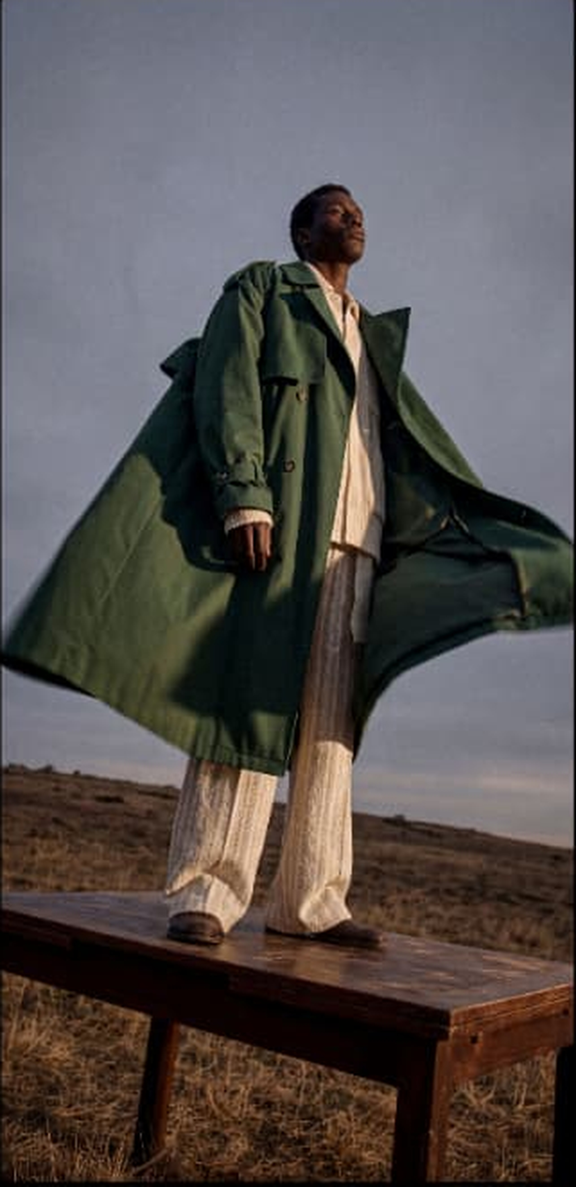 Man in a green coat standing on a bench