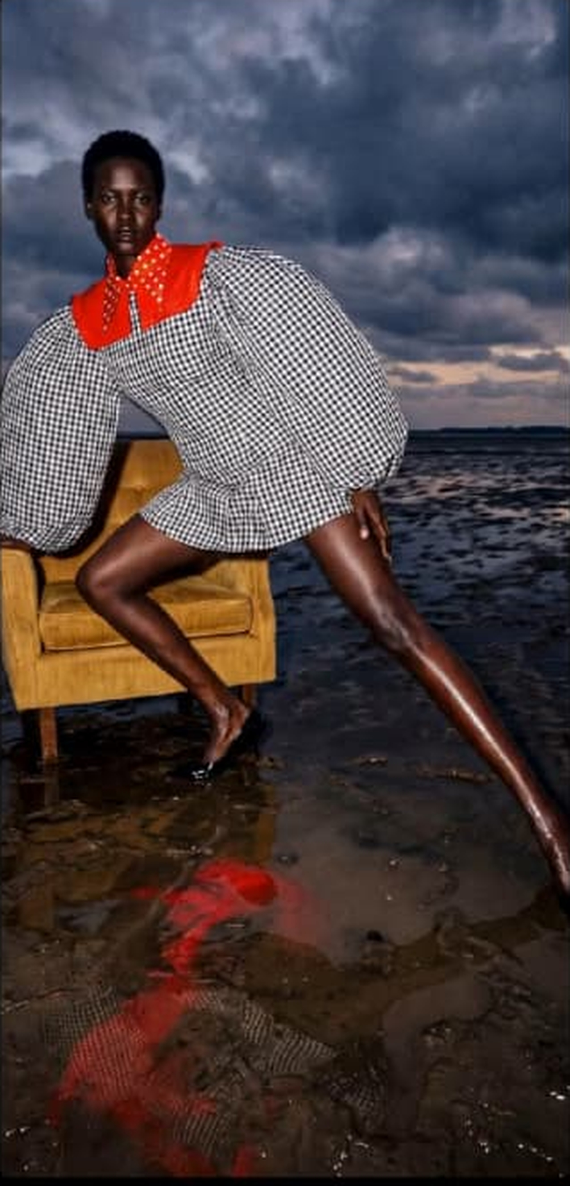 Fashion portrait seated on an ochre chair by the water